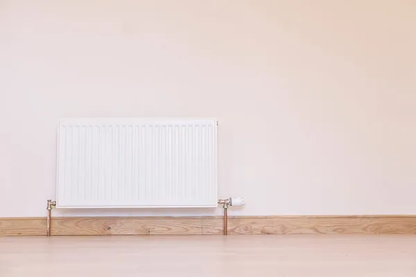 White panel radiator fitted on a plain wall, supplied and fitted by Phoenix